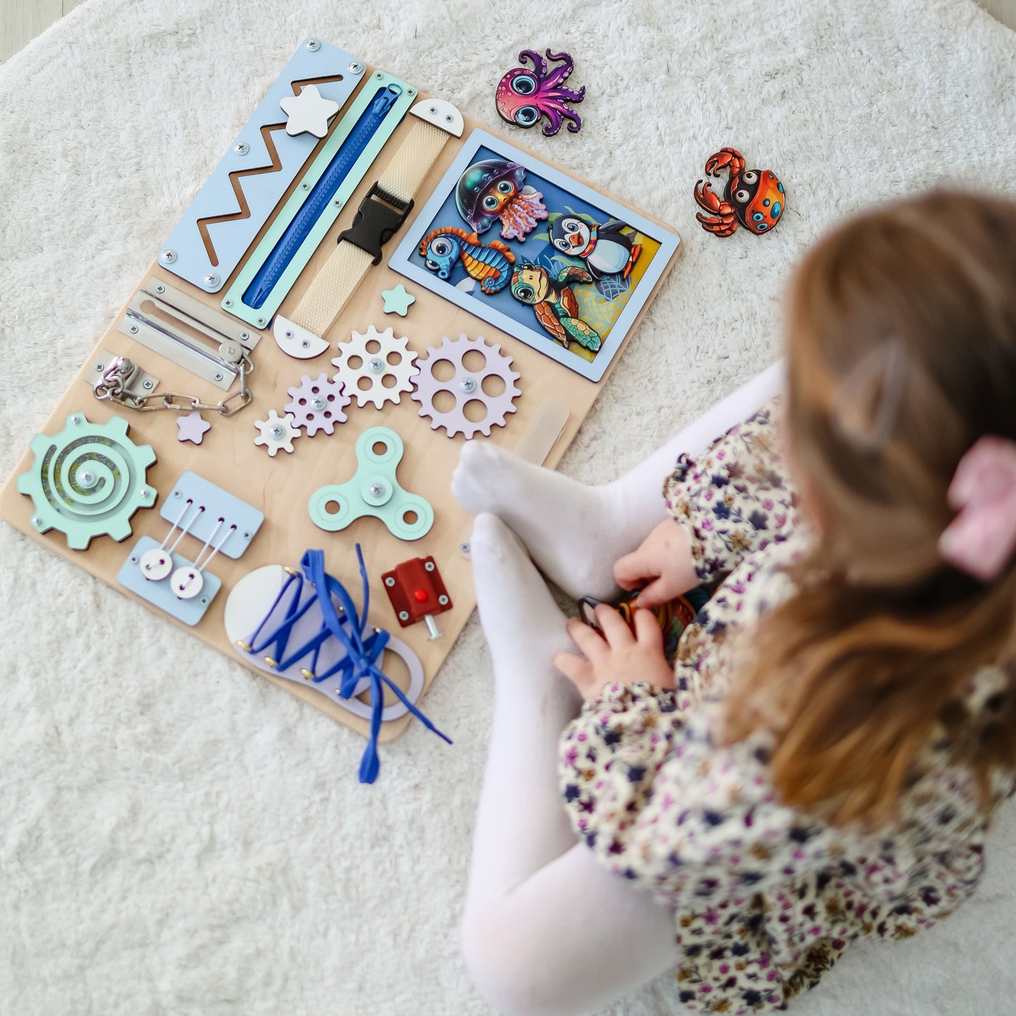 Toddler playing with an interactive underwater-themed busy board