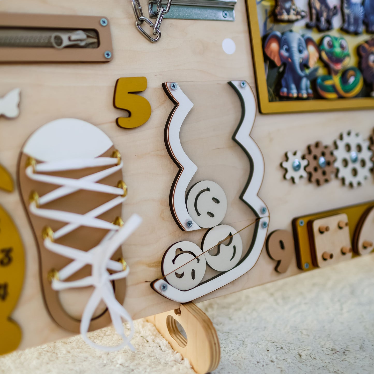 Close-up of removable lion, elephant, and zebra magnets on a wooden busy board
