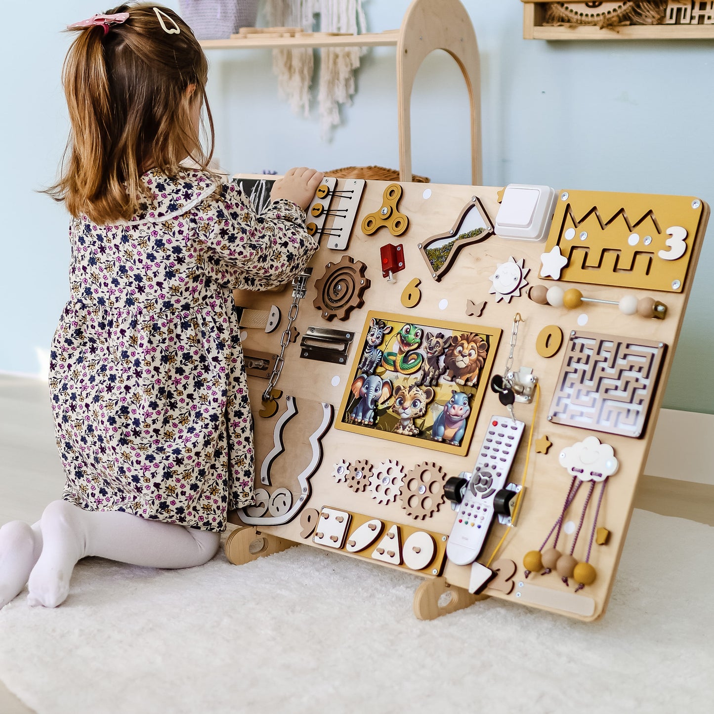 Toddler exploring animal habitats with a large wooden sensory board