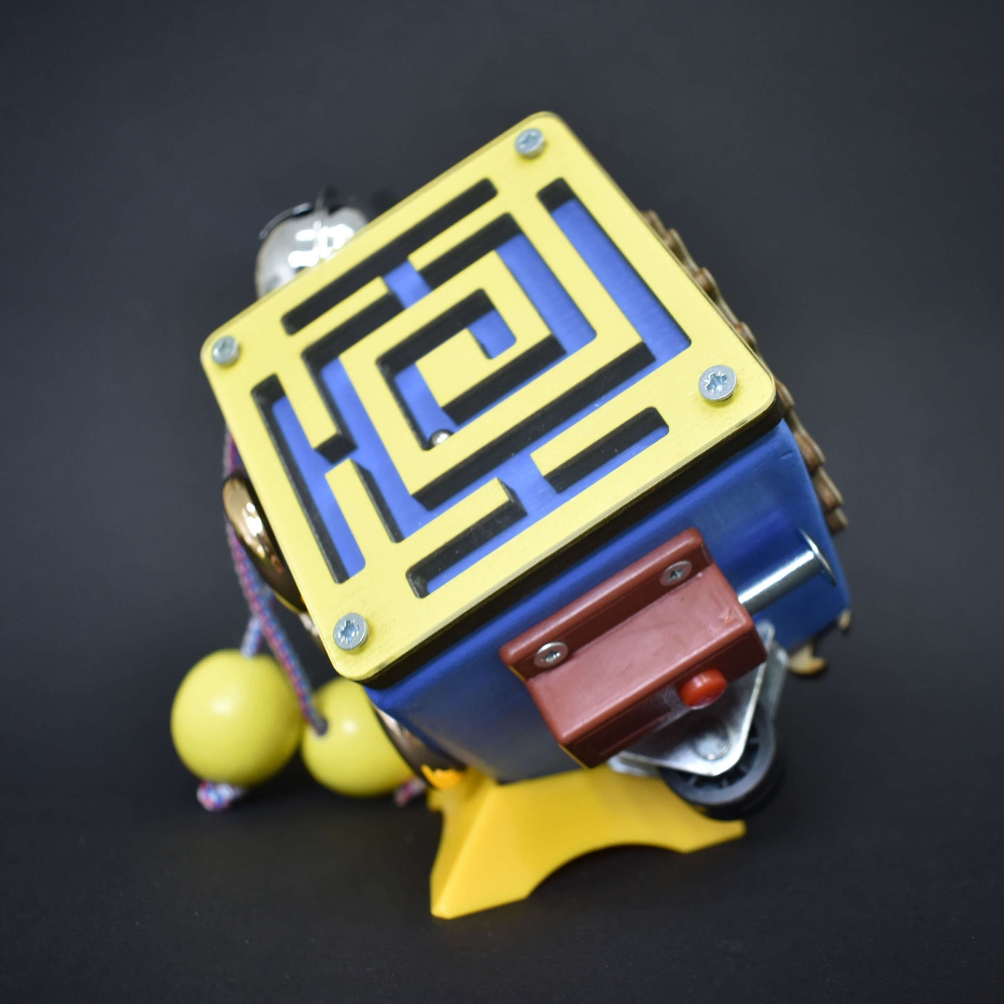 Busy cube attached to yellow stand for display