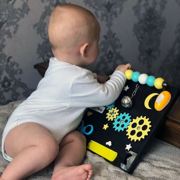 Close-up of toddler busy board with spinner and bell