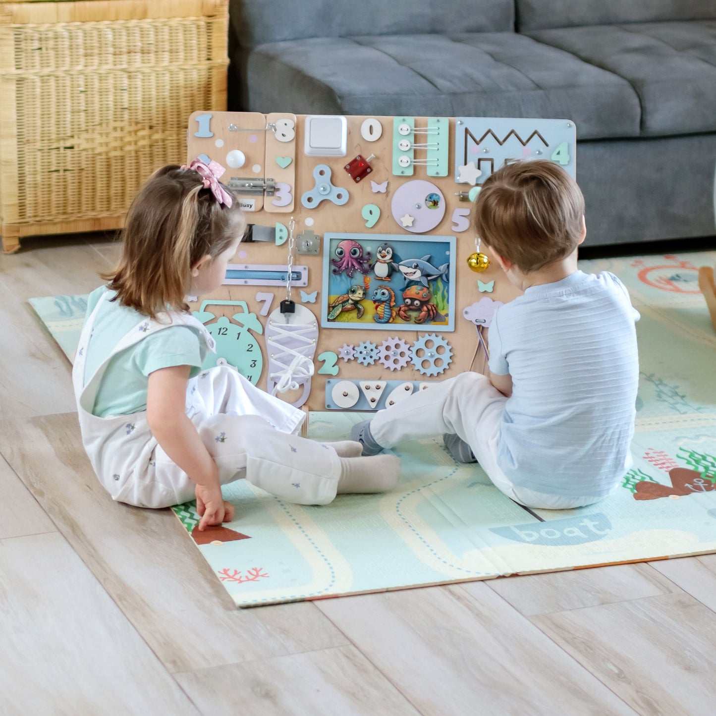 Toddler playing with a large Montessori ocean-themed busy board