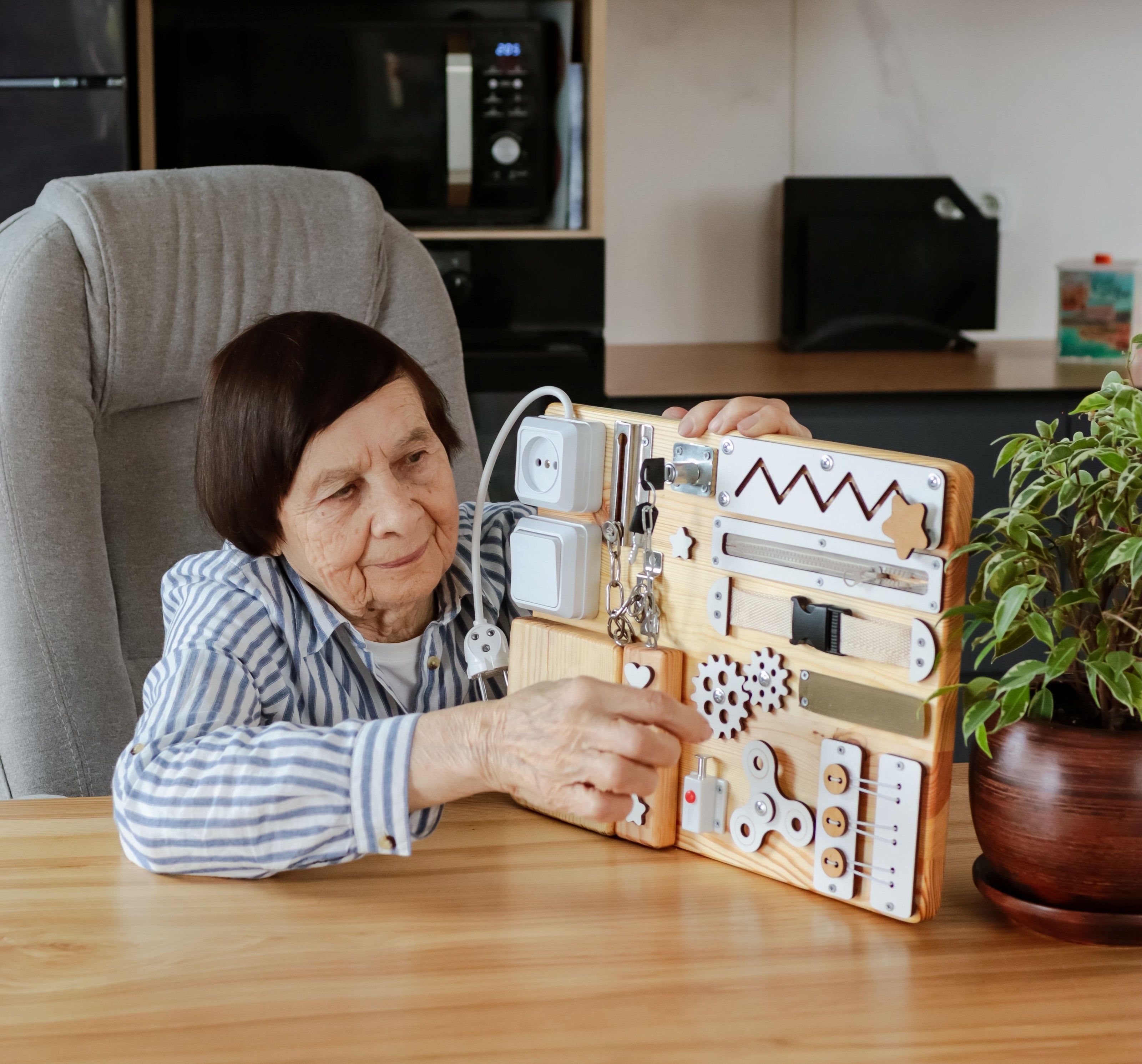 Elderly person using a Dementia Busy Board at home, engaging with interactive elements like switches, locks, and gears for cognitive stimulation