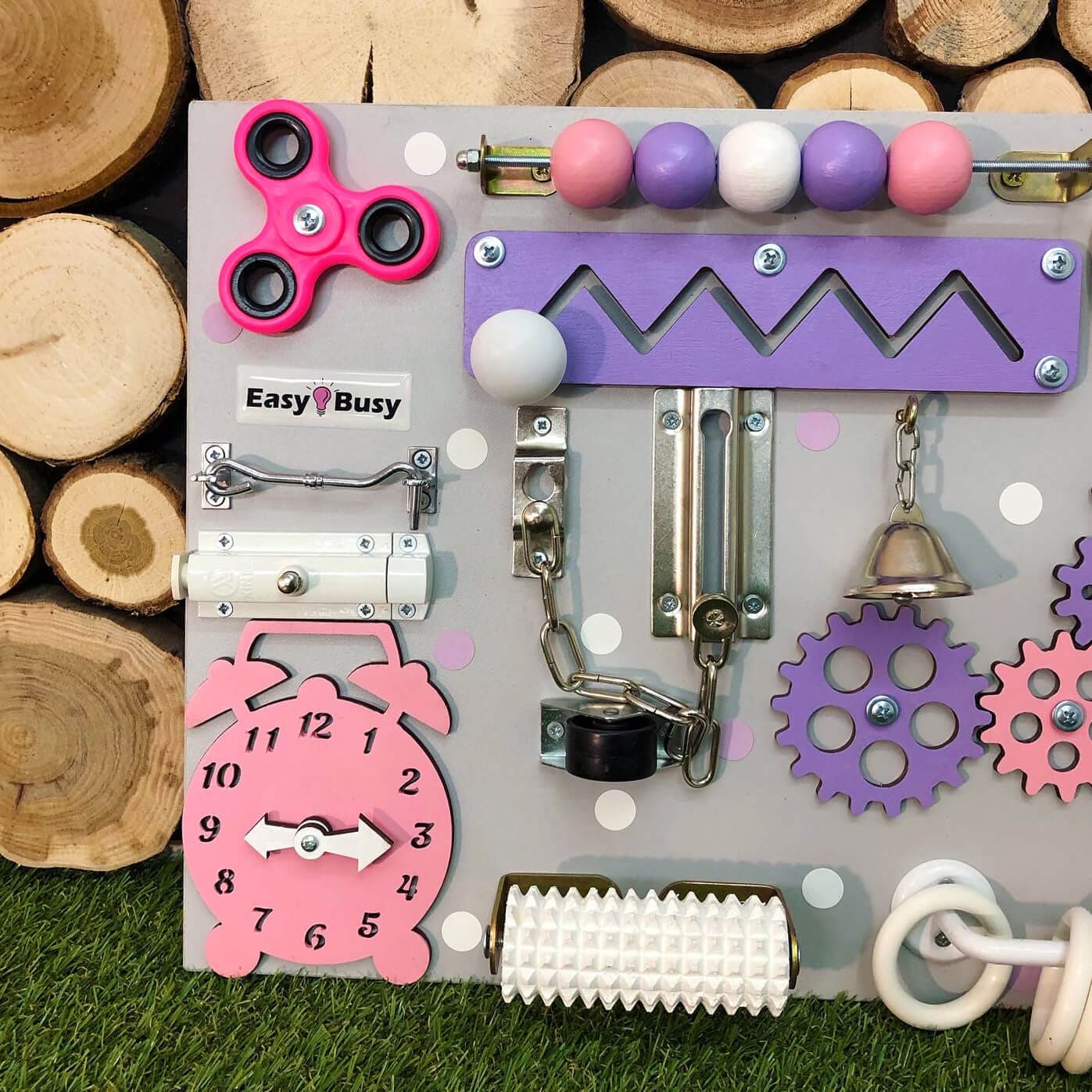 Travel-size busy board with pastel sensory components on a dotted gray background