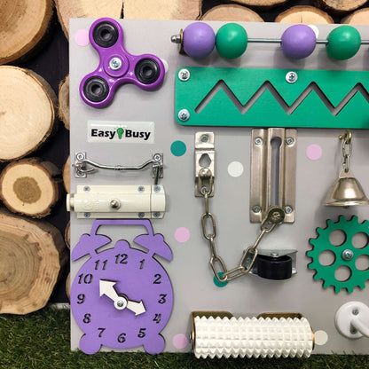 Handmade toddler busy board in soft pink and purple with interactive gears and switches