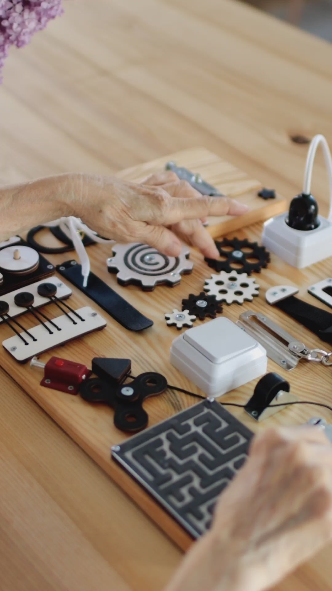 Demonstration of the Dementia Busy Board in use, showcasing interactive features like switches, gears, locks, and zippers designed to improve fine motor skills, cognitive function, and memory support for adults with dementia and Alzheimer's